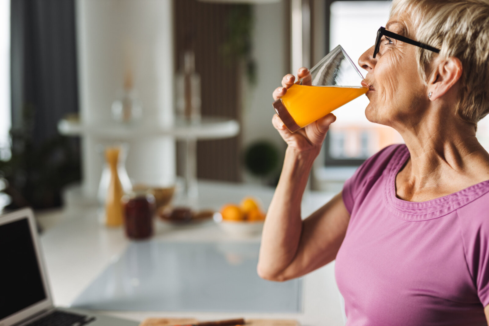 Senior woman drinking orange juice in order to strengthen the immune system.
