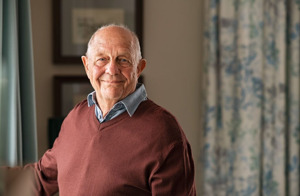 Happy senior man standing inside his apartment.