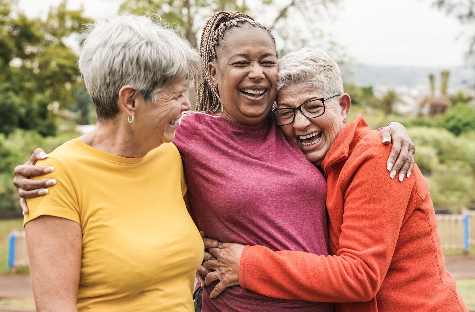 Happy senior woman standing outside laughing together.