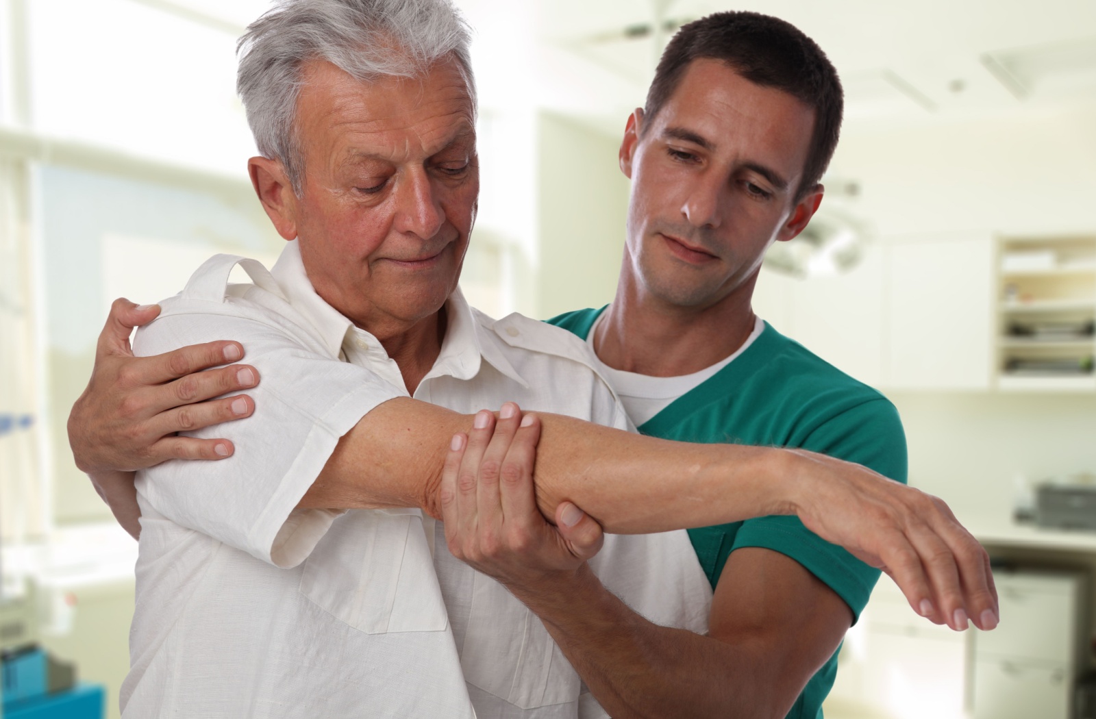 A healthcare professional assisting an elderly person with stretching their arm during a physiotherapy session.