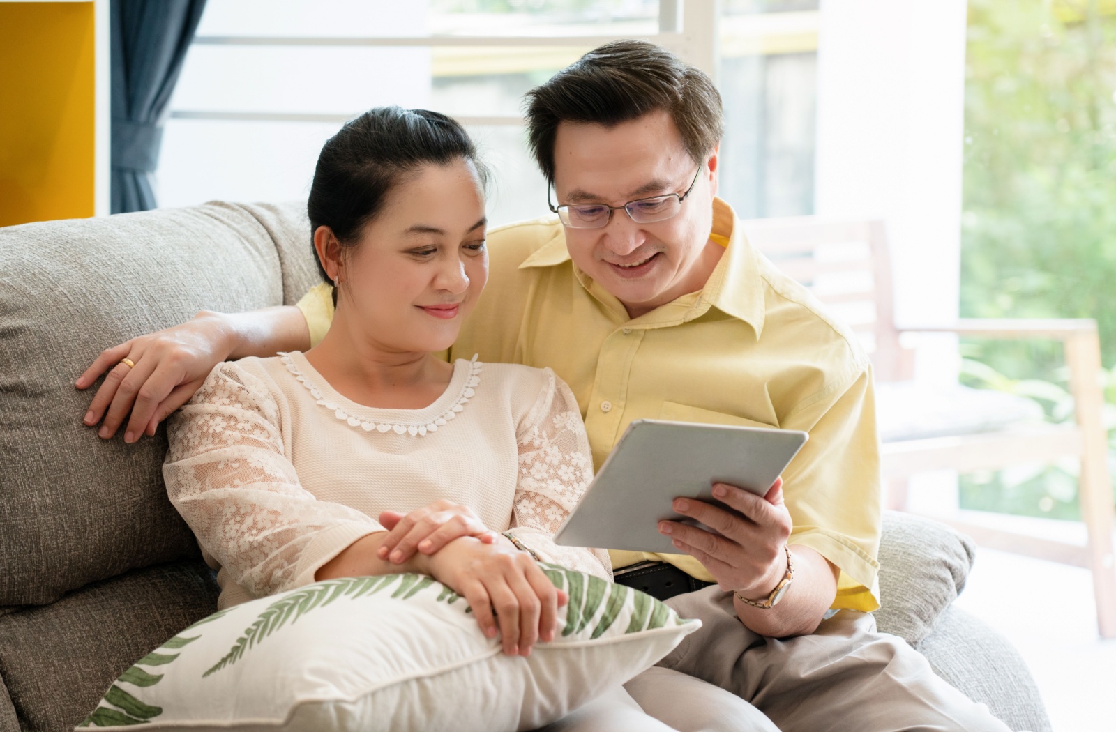 An older couple cuddles on a couch while researching independent living communities for retirement together