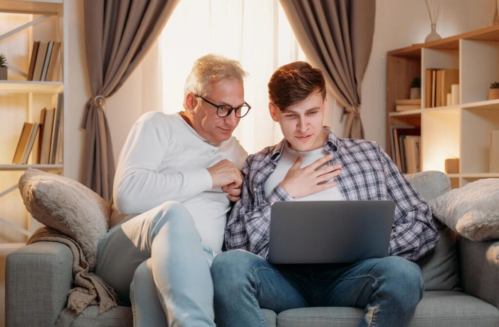 An adult and their senior parent research different assisted living communities on the computer.