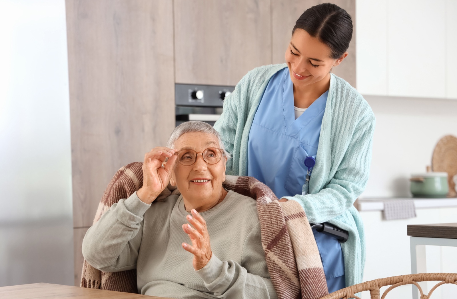a caregiver helping a senior with a blanket