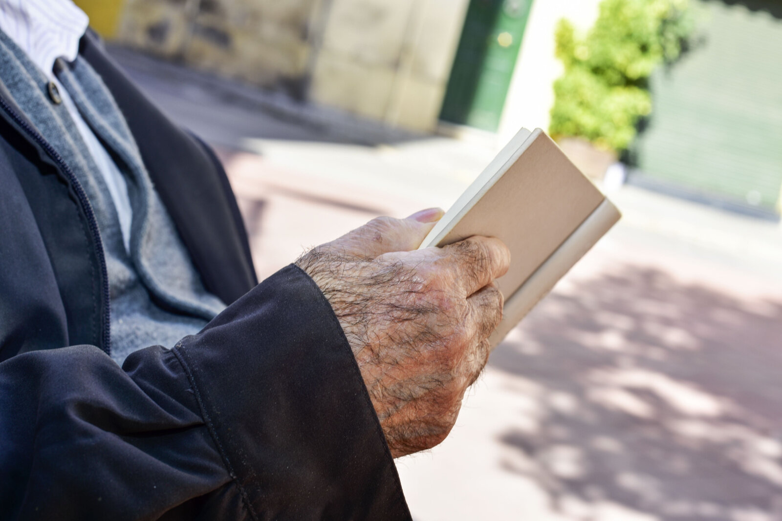 A hand of senior man is holding a book.