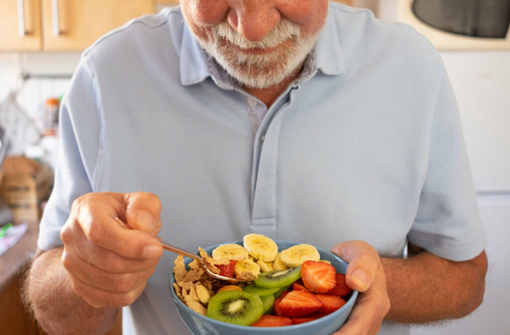 A senior man is eating a bowl of fruits and grains that are high in fiber to help with constipation.