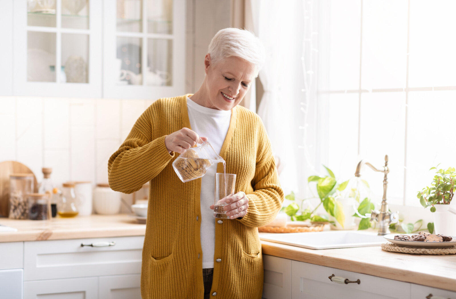 A senior woman is pouring water into a glass to drink to improve daytime sleepiness and help regulate sleep pattern