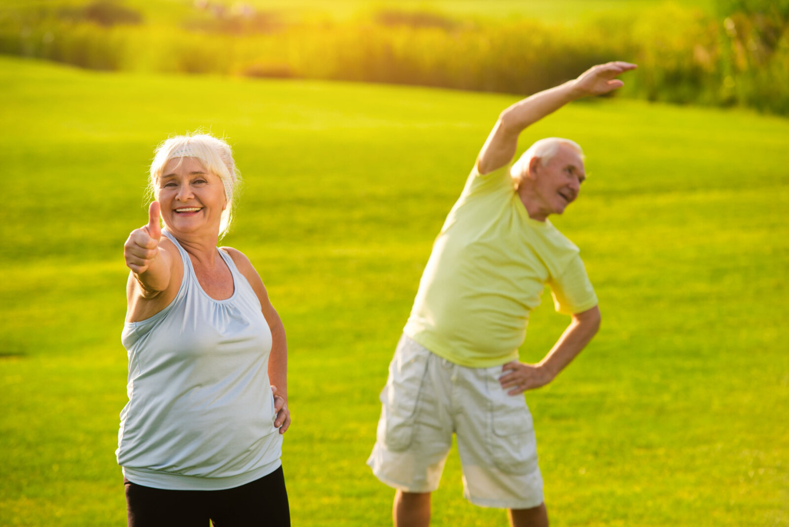 Senior couple doing exercises outside and enjoying fresh air.