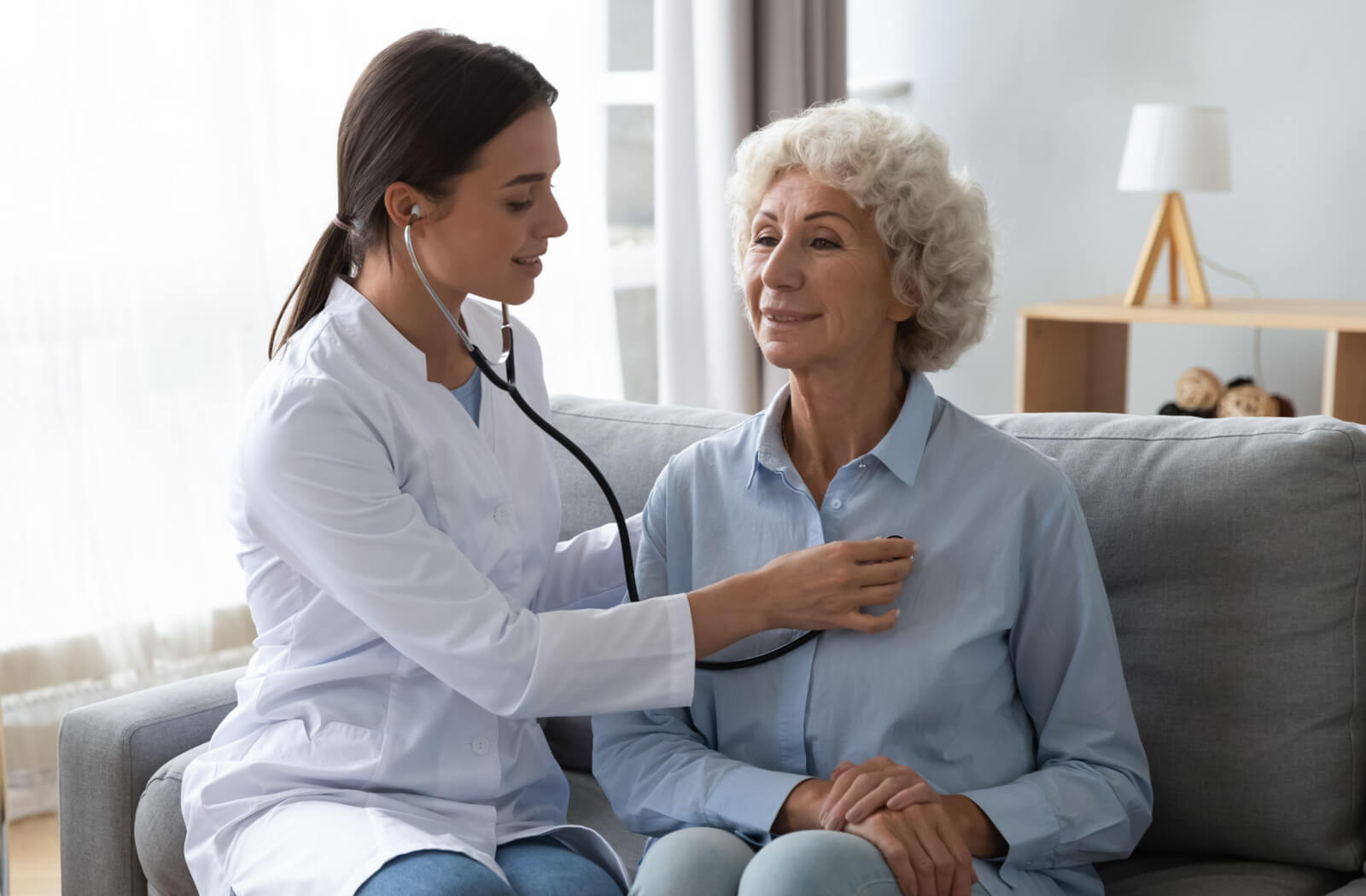 A female doctor performs a routine checkup on an elderly woman.