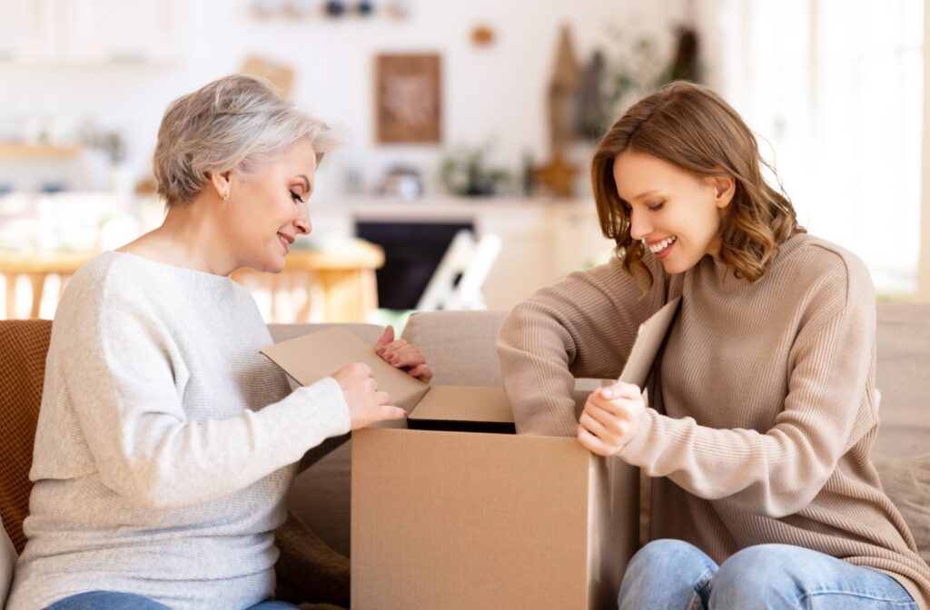 An older adult mother and her young daughter unpacking a cardboard box.