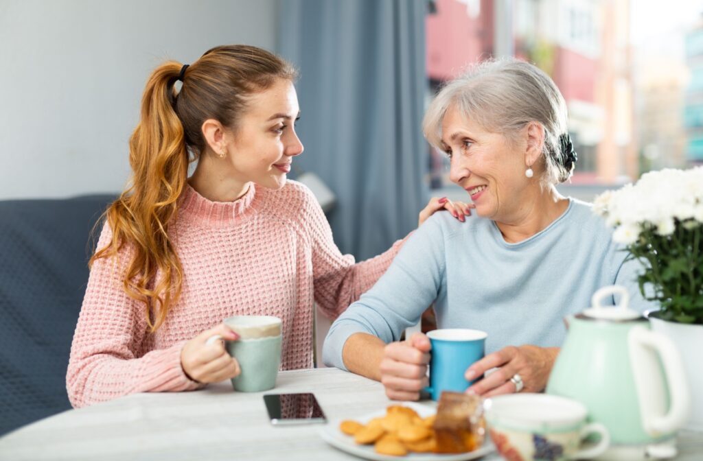 A young woman and an older adult woman enjoying a conversation over a cup of coffee and some snacks.