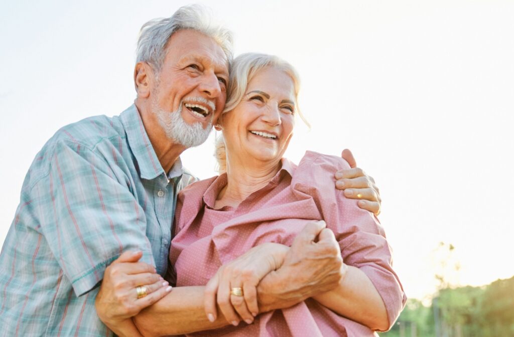 A close-up image of senior couple laughing and hugging while having fun outdoors in the park.