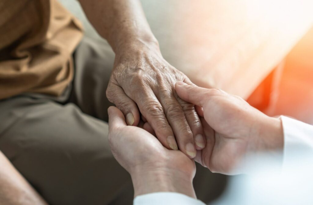 A close-up of a loved one holding the outstretched hand of their elderly parent with diabetes.