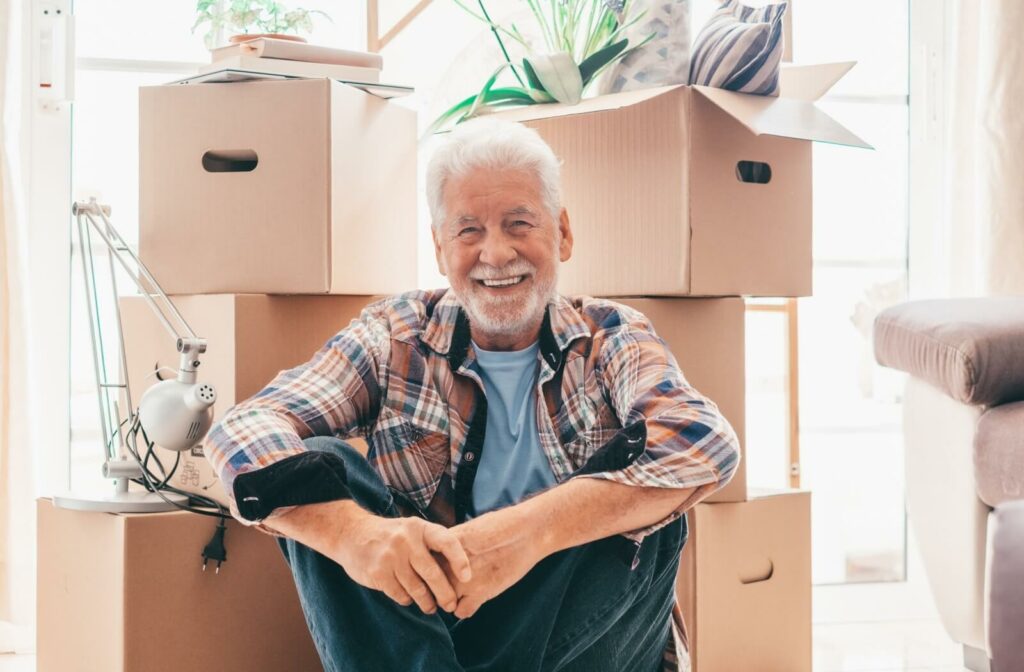 An older man moving into his new assisted living apartment sits with his belongings packed behind him.