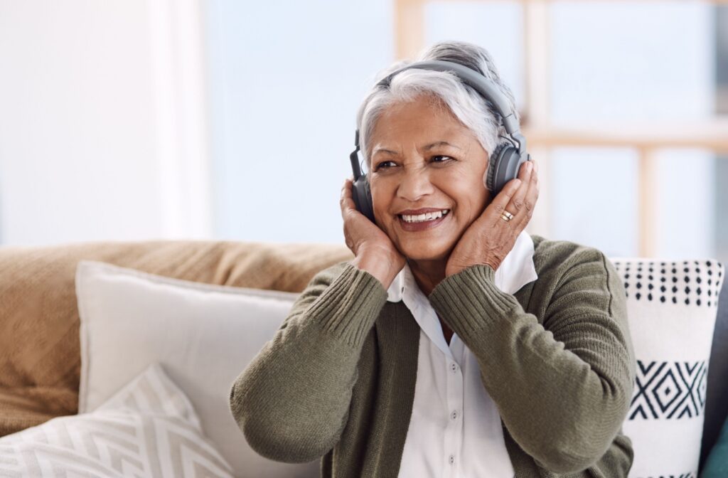 An older adult touching their cheeks and surprise while listening to an audiobooks through headphones.