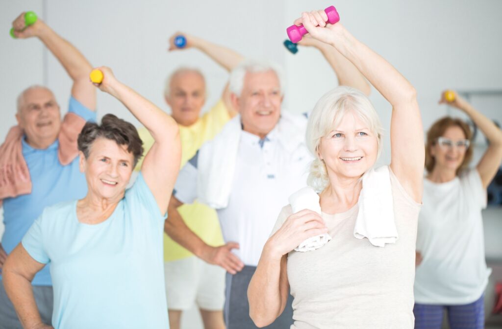 A group of older adults in independent living doing exercises with dumbbells in a fitness class.