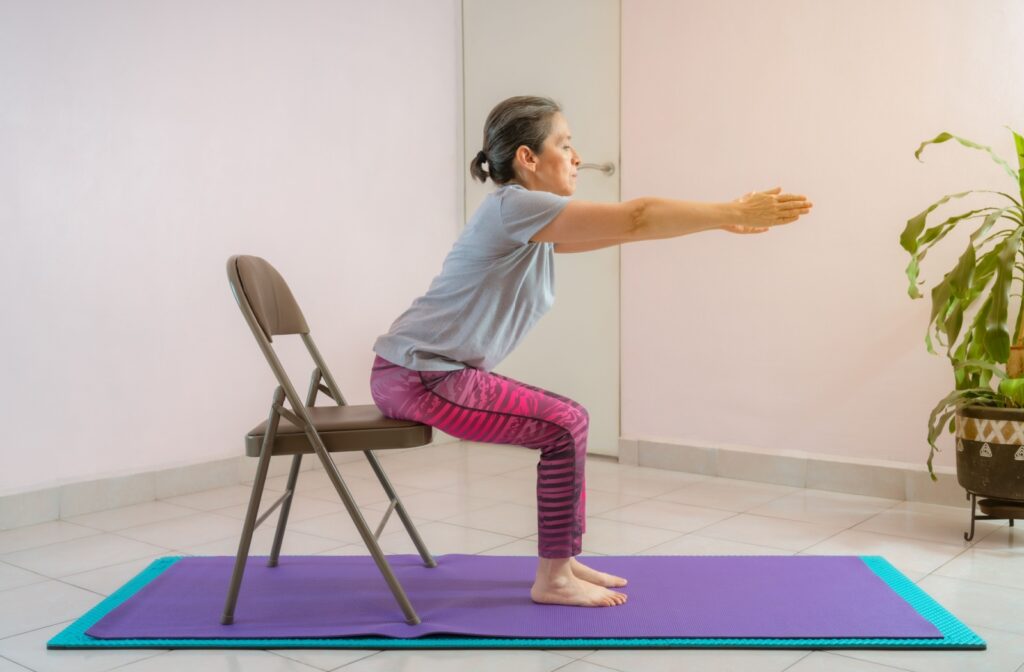 An older woman performing an exercise with a chair for support, focusing on balance.