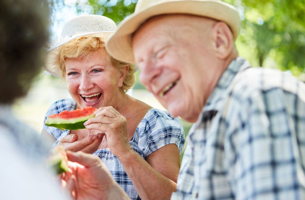Older adult enjoying watermelon at a sunny picnic with friends during a summer outing